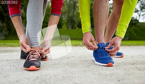 Image of close up of couple tying shoelaces outdoors