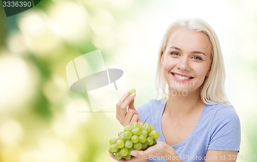 Image of happy woman eating grapes