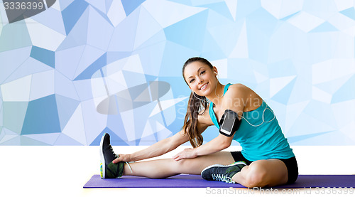 Image of smiling woman stretching leg on mat over low poly
