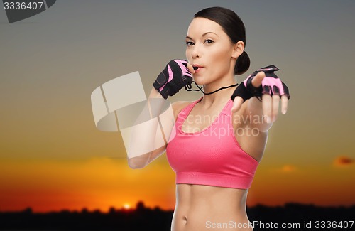 Image of woman coach blowing whistle over sunset skyline