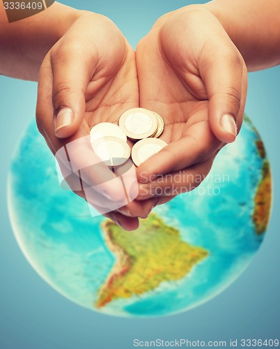 Image of cupped hands holding euro coins over earth globe