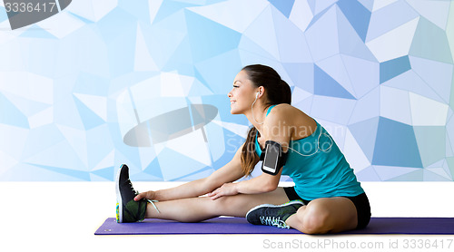 Image of smiling woman stretching leg on mat over low poly