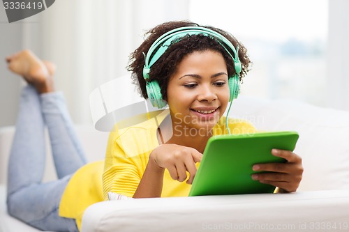 Image of happy african woman with tablet pc and headphones