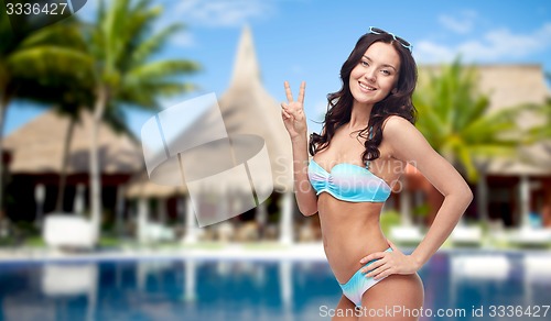 Image of happy woman in swimsuit showing victory hand sign