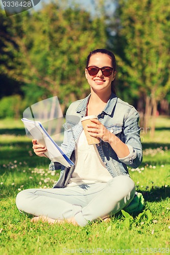 Image of smiling young girl with notebook and coffee cup