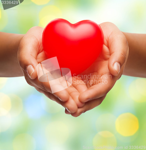 Image of close up of female hands holding small red heart