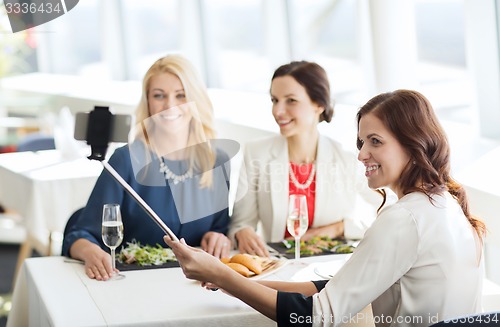 Image of women with smartphone taking selfie at restaurant