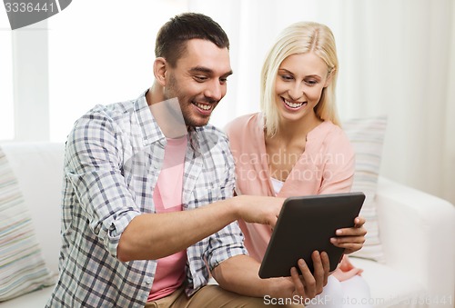 Image of smiling happy couple with tablet pc at home