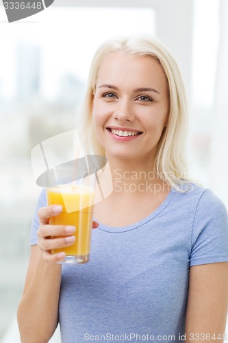 Image of smiling woman drinking orange juice at home