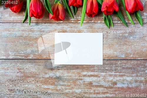 Image of close up of red tulips and blank paper or letter