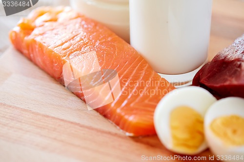 Image of close up of salmon fillets, eggs and milk on table