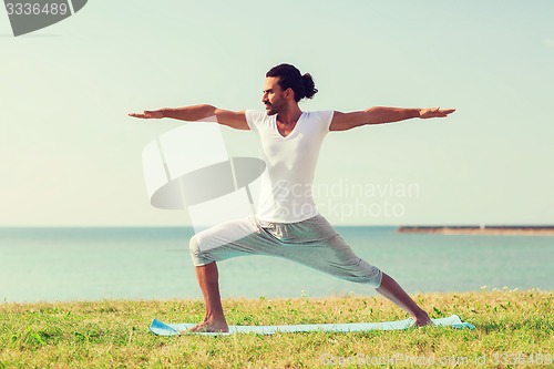 Image of smiling man making yoga exercises outdoors