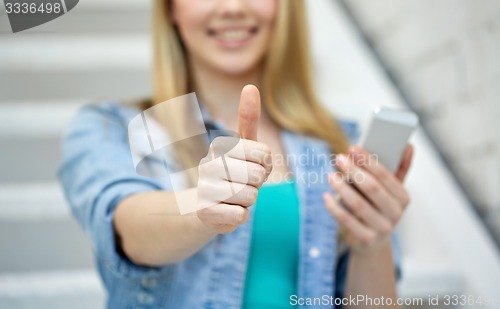 Image of female with smartphone showing thumbs up