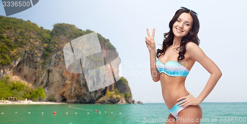 Image of happy woman in swimsuit showing victory hand sign