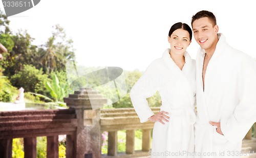 Image of happy couple in bathrobes over spa hotel resort