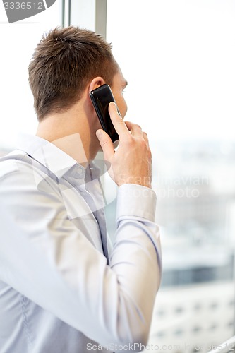 Image of businessman calling on smartphone in office