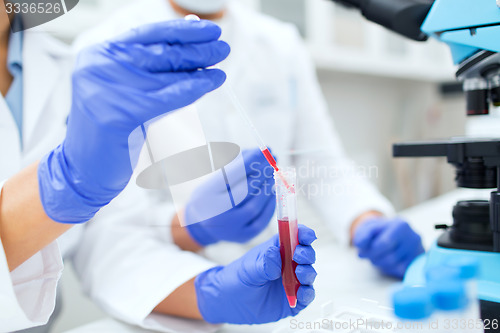 Image of close up of scientists filling test tube in lab