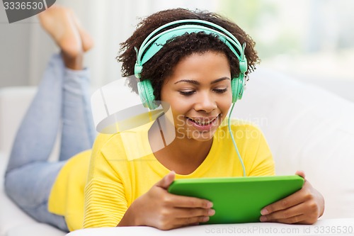 Image of happy african woman with tablet pc and headphones
