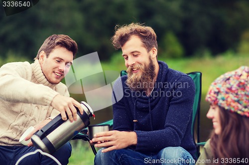 Image of group of smiling tourists cooking food in camping