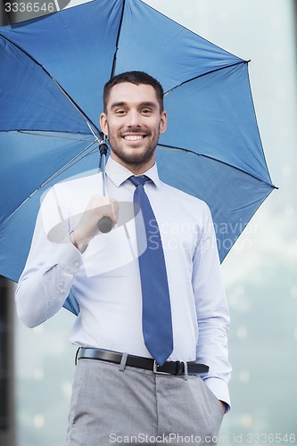 Image of young smiling businessman with umbrella outdoors