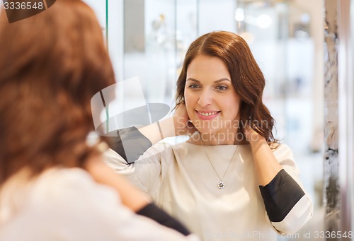 Image of happy woman choosing pendant at jewelry store