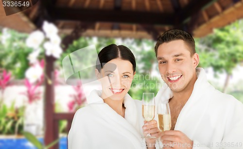 Image of happy couple in bathrobes with champagne at resort