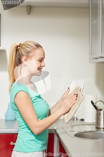 Image of happy woman wiping dishes at home kitchen