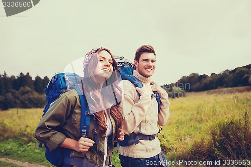 Image of smiling couple with backpacks hiking