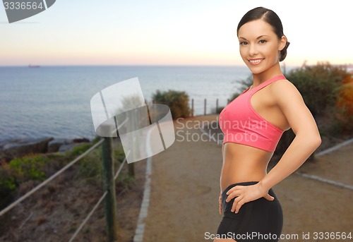 Image of smiling sporty asian woman over beach background