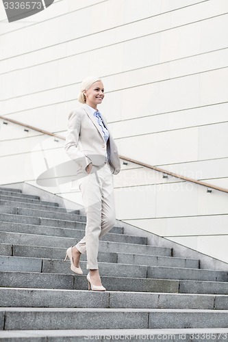 Image of young smiling businesswoman walking down stairs