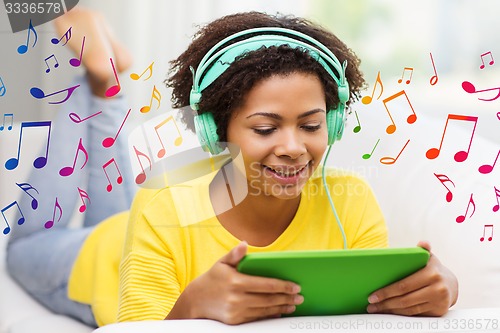 Image of happy african woman with tablet pc and headphones