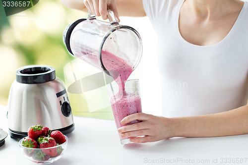 Image of close up of woman with blender pouring milk shake