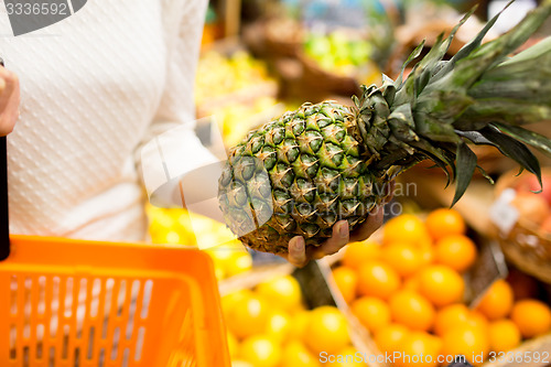 Image of close up of woman with pineapple in grocery market
