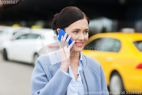 Image of smiling woman with smartphone over taxi in city