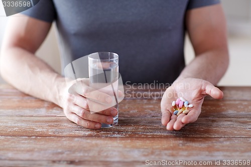 Image of close up of male hands holding pills and water