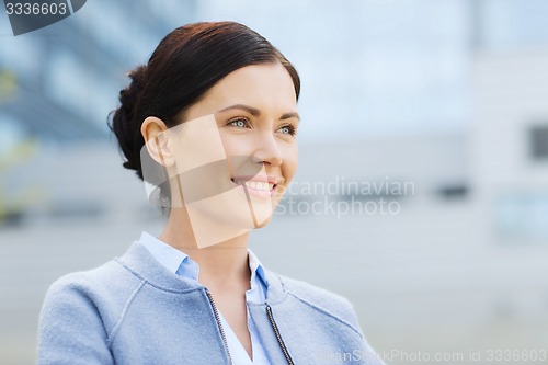 Image of young smiling businesswoman over office building