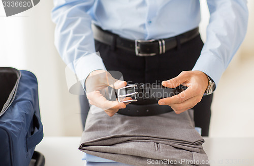 Image of businessman packing clothes into travel bag