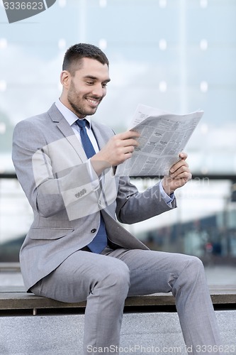 Image of young smiling businessman newspaper outdoors