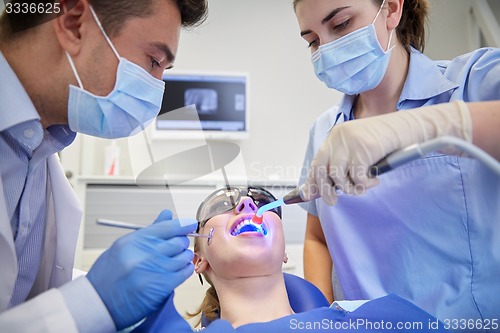 Image of dentists treating woman patient teeth at clinic