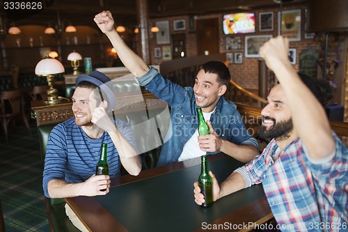 Image of happy male friends drinking beer at bar or pub