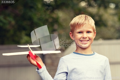 Image of smiling little boy holding a wooden airplane model