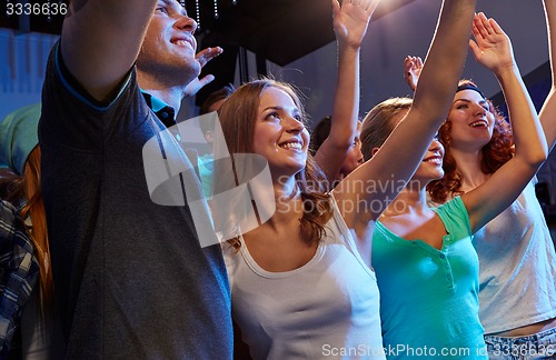 Image of smiling friends at concert in club