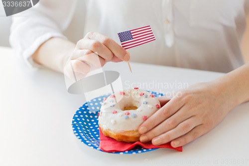Image of female hands decorating donut with american flag