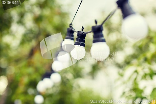 Image of close up of bulb garland hanging in rainy garden