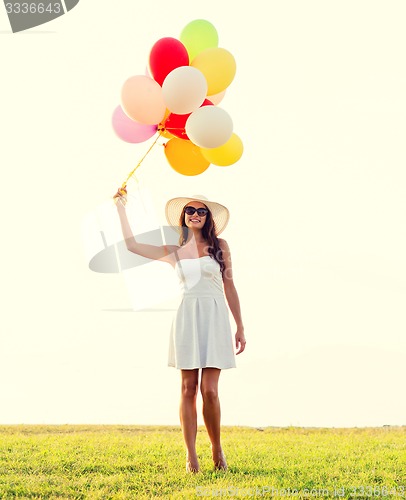 Image of smiling young woman in sunglasses with balloons