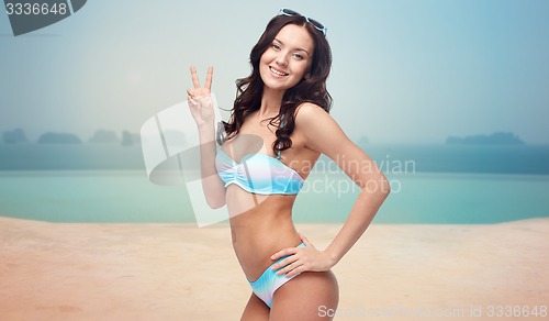 Image of happy woman in swimsuit showing victory hand sign