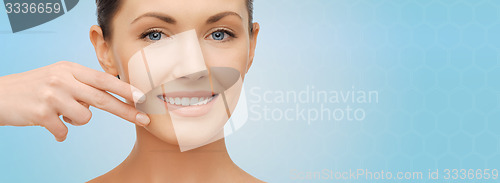 Image of face and hand of smiling woman over blue