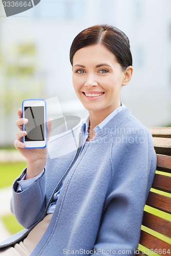 Image of young smiling businesswoman showing smartphone