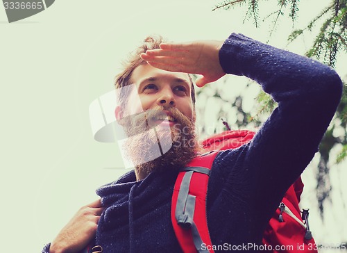 Image of smiling man with beard and backpack hiking