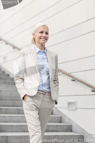 Image of young smiling businesswoman walking down stairs